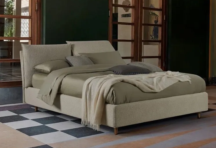 Moderno letto beige con lenzuola stropicciate in un'elegante camera da letto con tappeto a quadri e pareti verde scuro.