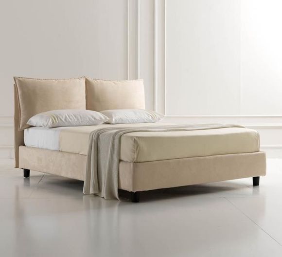 Divanetto beige in un soggiorno con parete marrone, quadri incorniciati e fiori su un tavolino.