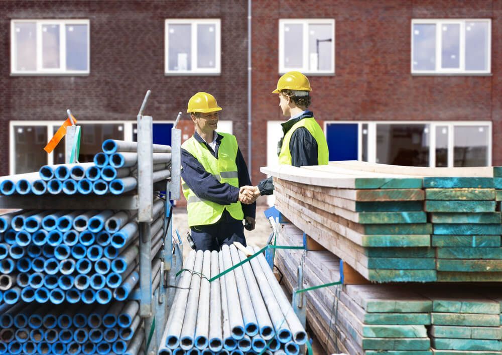 Two Construction Workers Shaking Hands in Front of a Building — Cemak Constructions in Sawtell, NSW