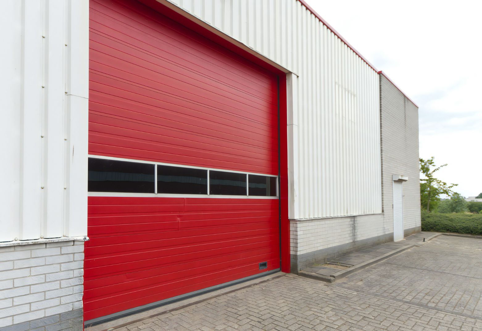 Industrial Warehouse With Red Roller Door — Cemak Constructions in Forster-Tuncurry, NSW