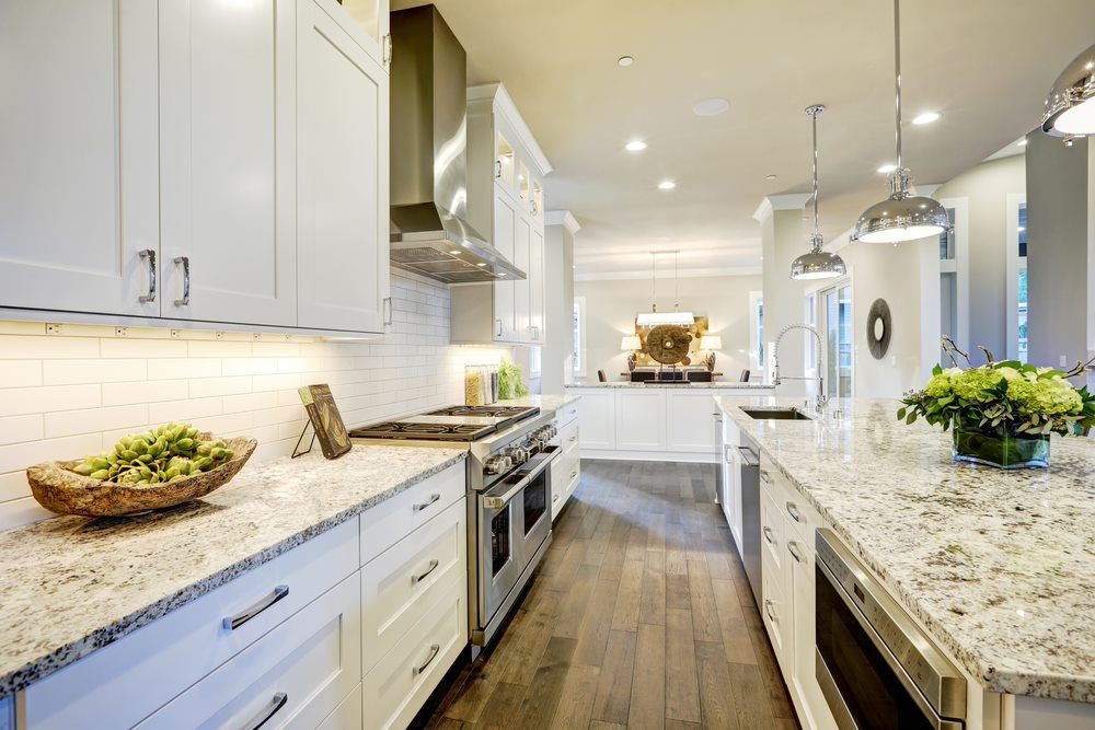 A Kitchen with White Cabinets and Granite Counter Tops — Cemak Constructions in Port Macquarie, NSW