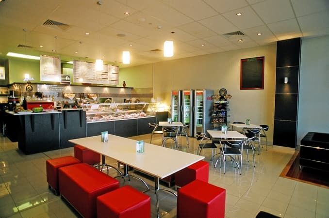 A Restaurant with Tables and Chairs and Red Ottomans — Cemak Constructions in Port Macquarie, NSW