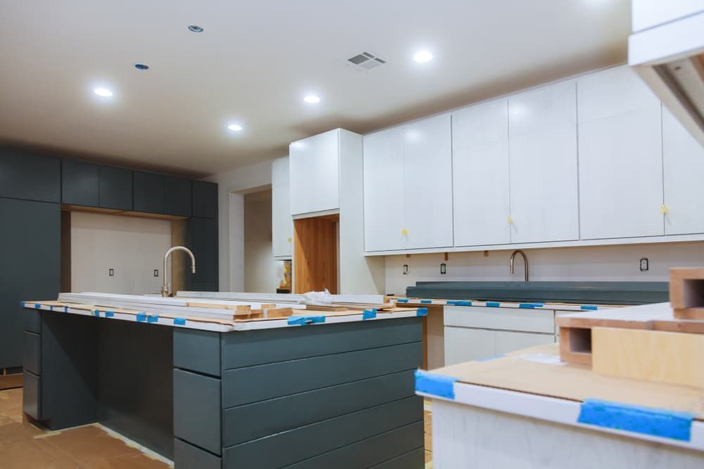 A Kitchen Under Construction with White Cabinets and A Large Island — Cemak Constructions in Urunga, NSW