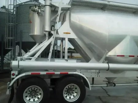 White cement tanker trailer with dual axles parked in an industrial area