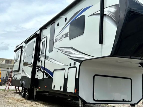 Large white and gray fifth-wheel RV parked outdoors in a residential area