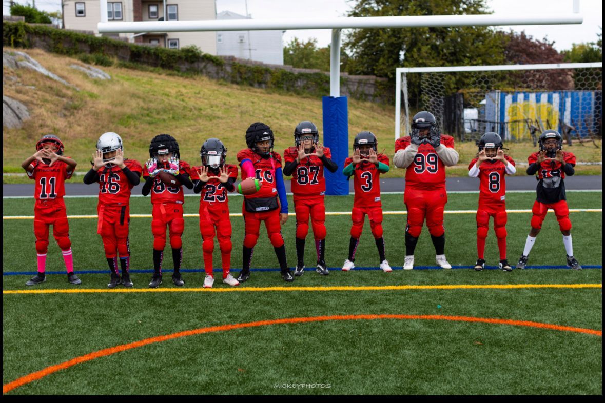 Youth football players in red uniforms lined up on a field for a team photo