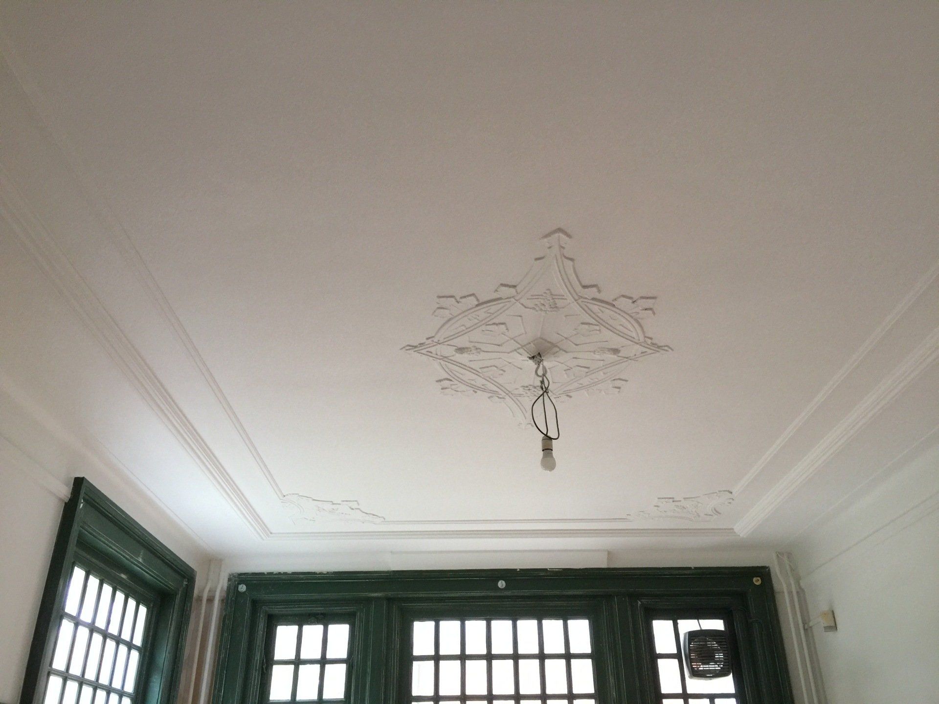 Een gerestaureerd plafond die gespoten is in witte verf.