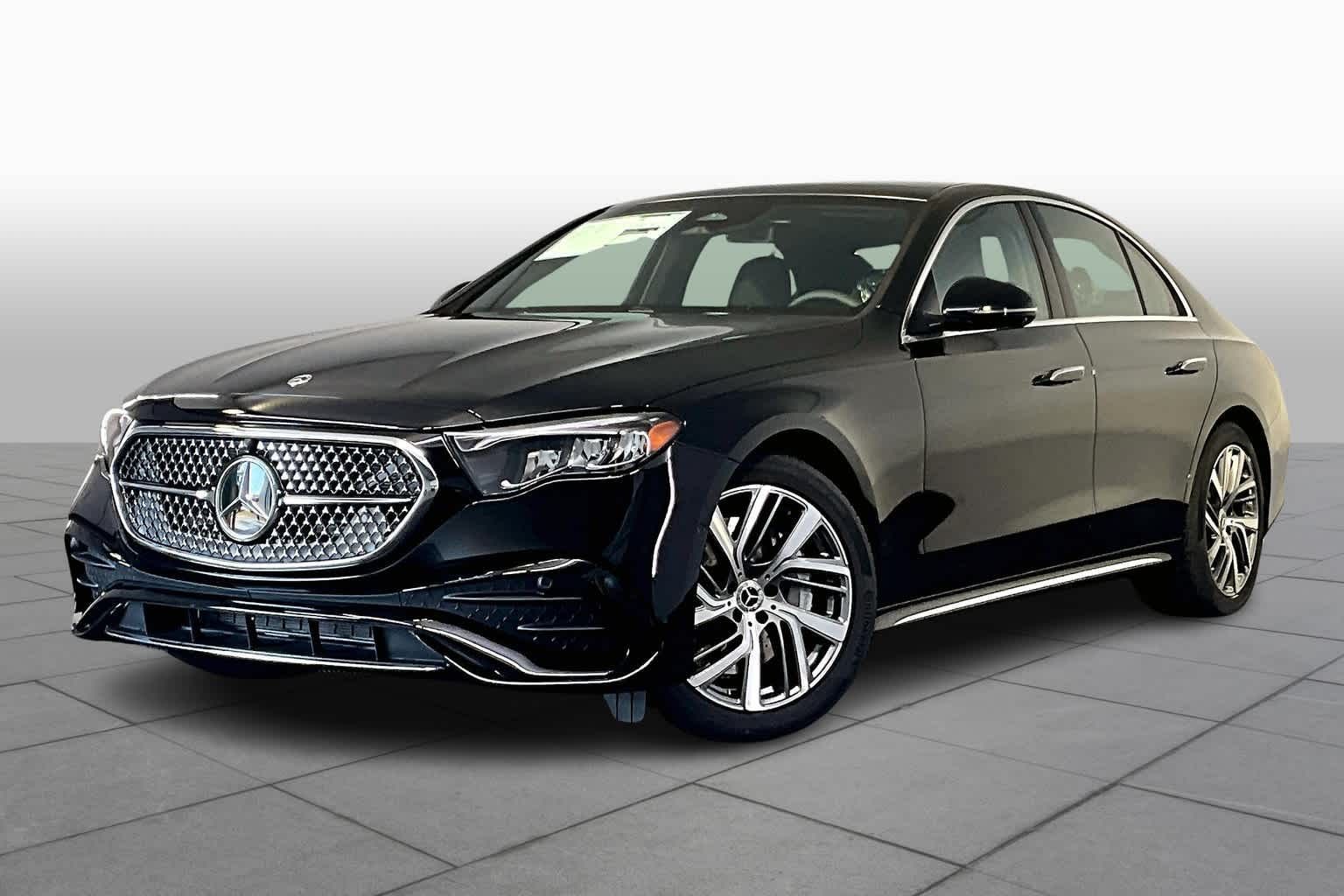 Black Mercedes sedan on a white background, angled view showing front grille and wheel.