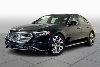 Black Mercedes-Benz sedan with silver wheels parked indoors. Front view, angled right.