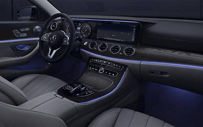 Interior view of a Mercedes-Benz car dashboard, dark gray with blue ambient lighting.