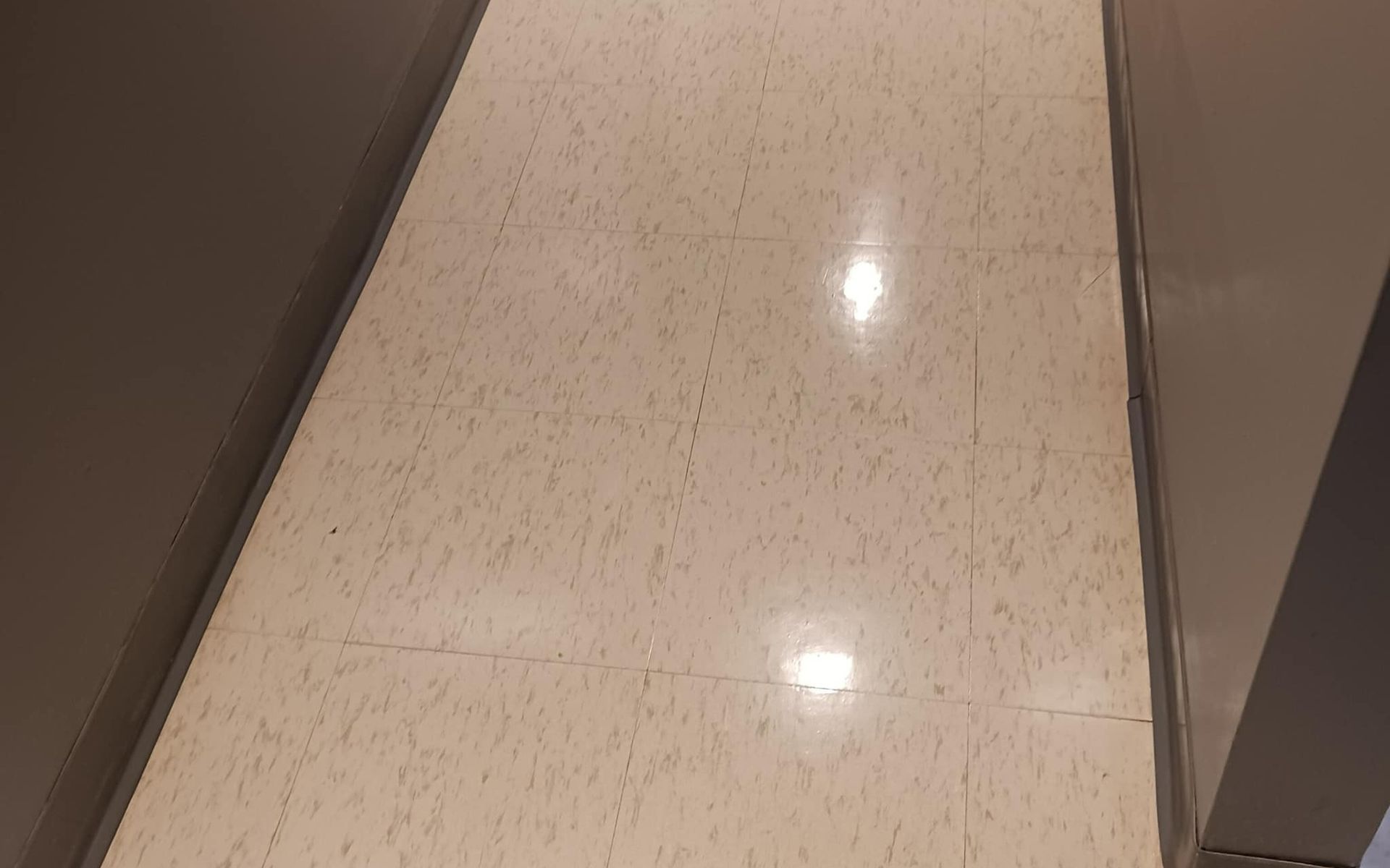 Tan tiled hallway with two tan walls on either side.