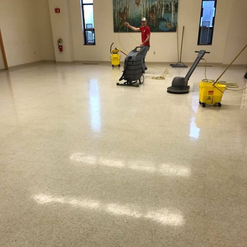 Tan tiled floor with a black wheeled suitcase.