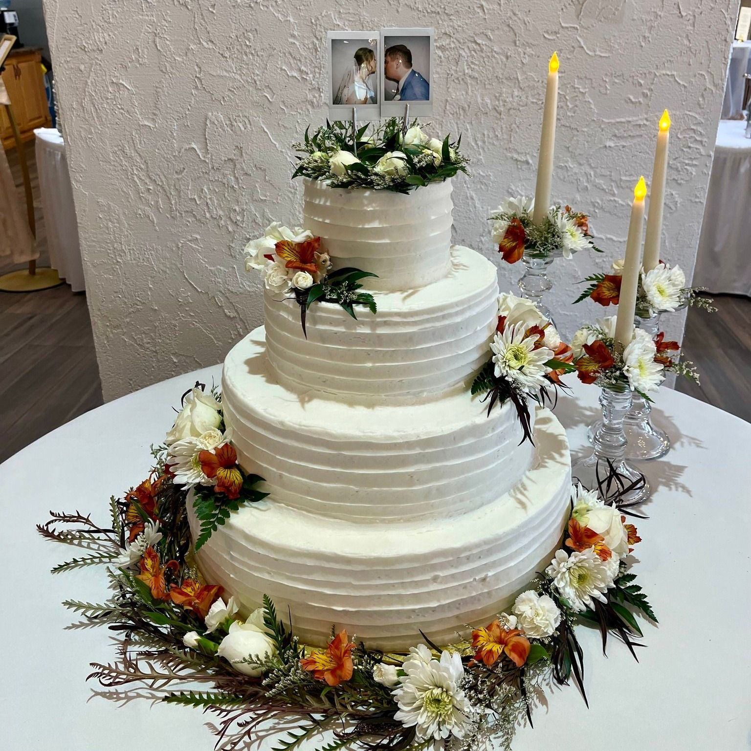 wedding cake with flowers and polaroids of bride and groom as topper