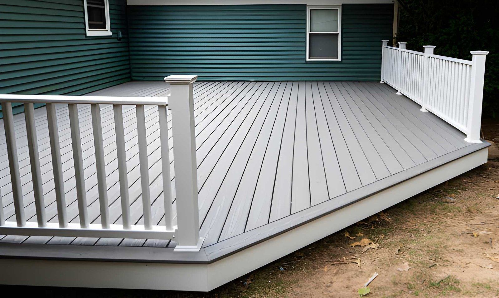 Raised gray deck with white railings beside a green house exterior