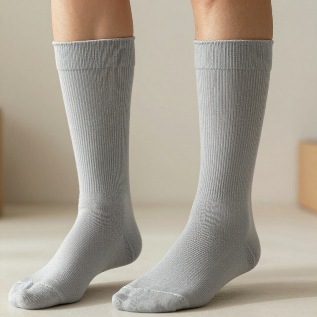 Dos piernas con calcetines hasta la rodilla de color gris claro de pie sobre un suelo claro.