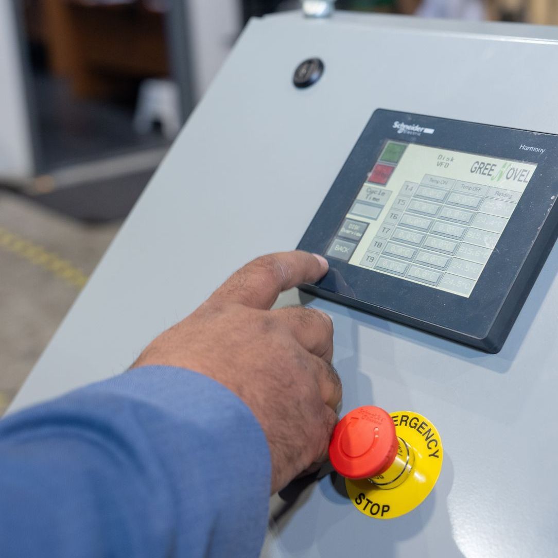 A person is pressing an emergency stop button on a control panel