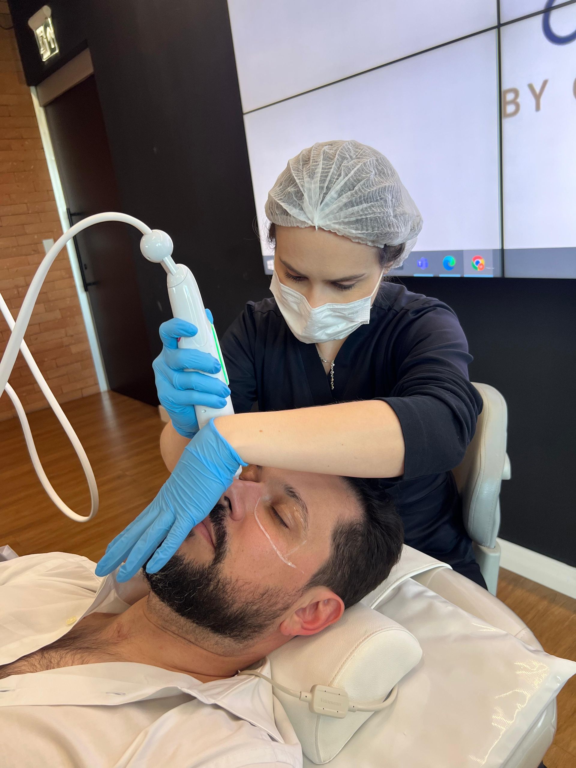A man with a beard is getting a treatment from a woman