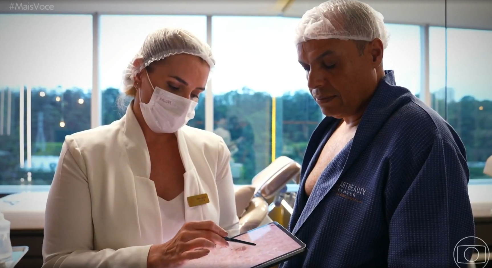 A woman wearing a mask is talking to a man in a bathrobe.