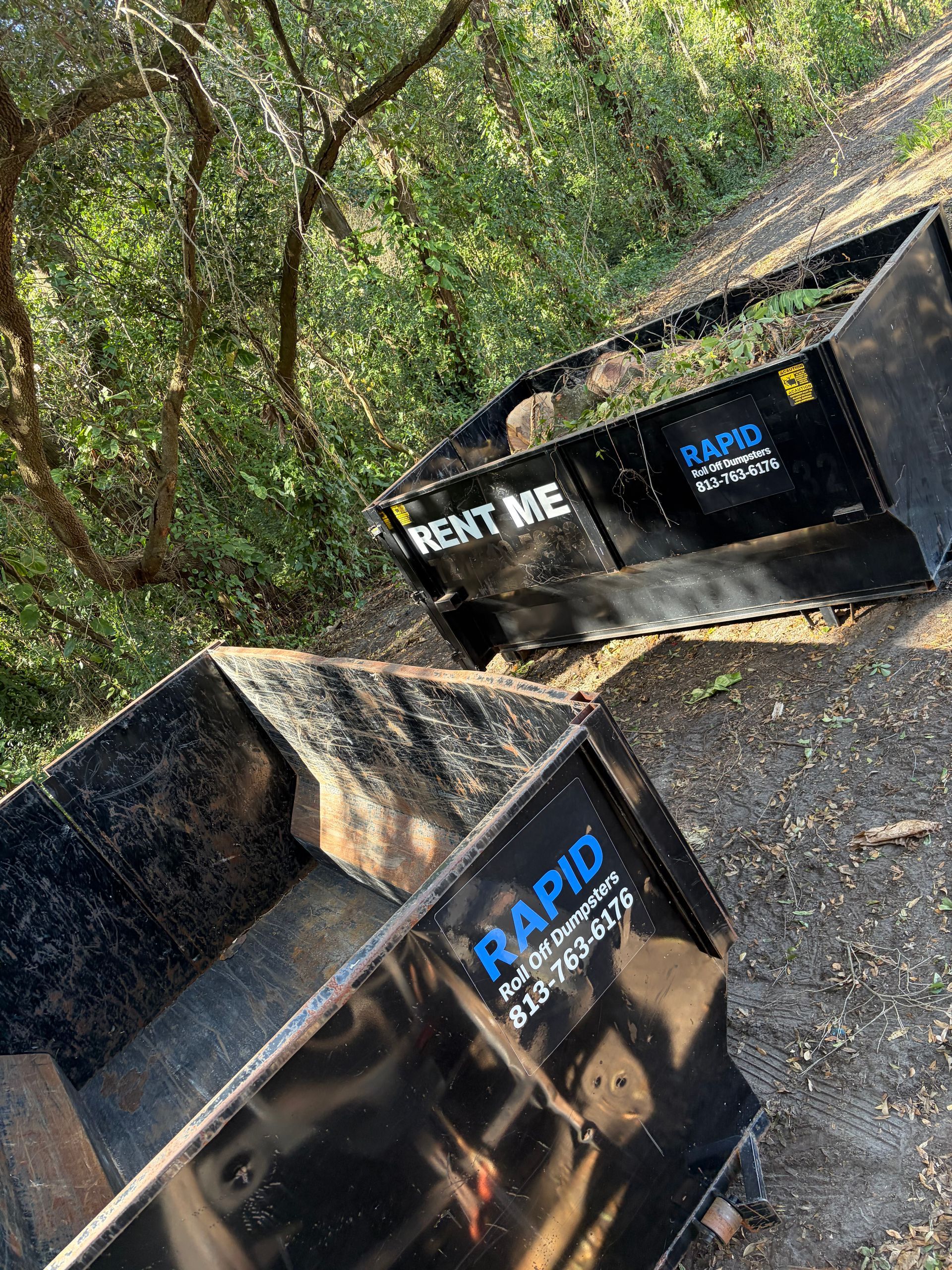 Bright green industrial dumpster on asphalt in an outdoor lot under a clear blue sky