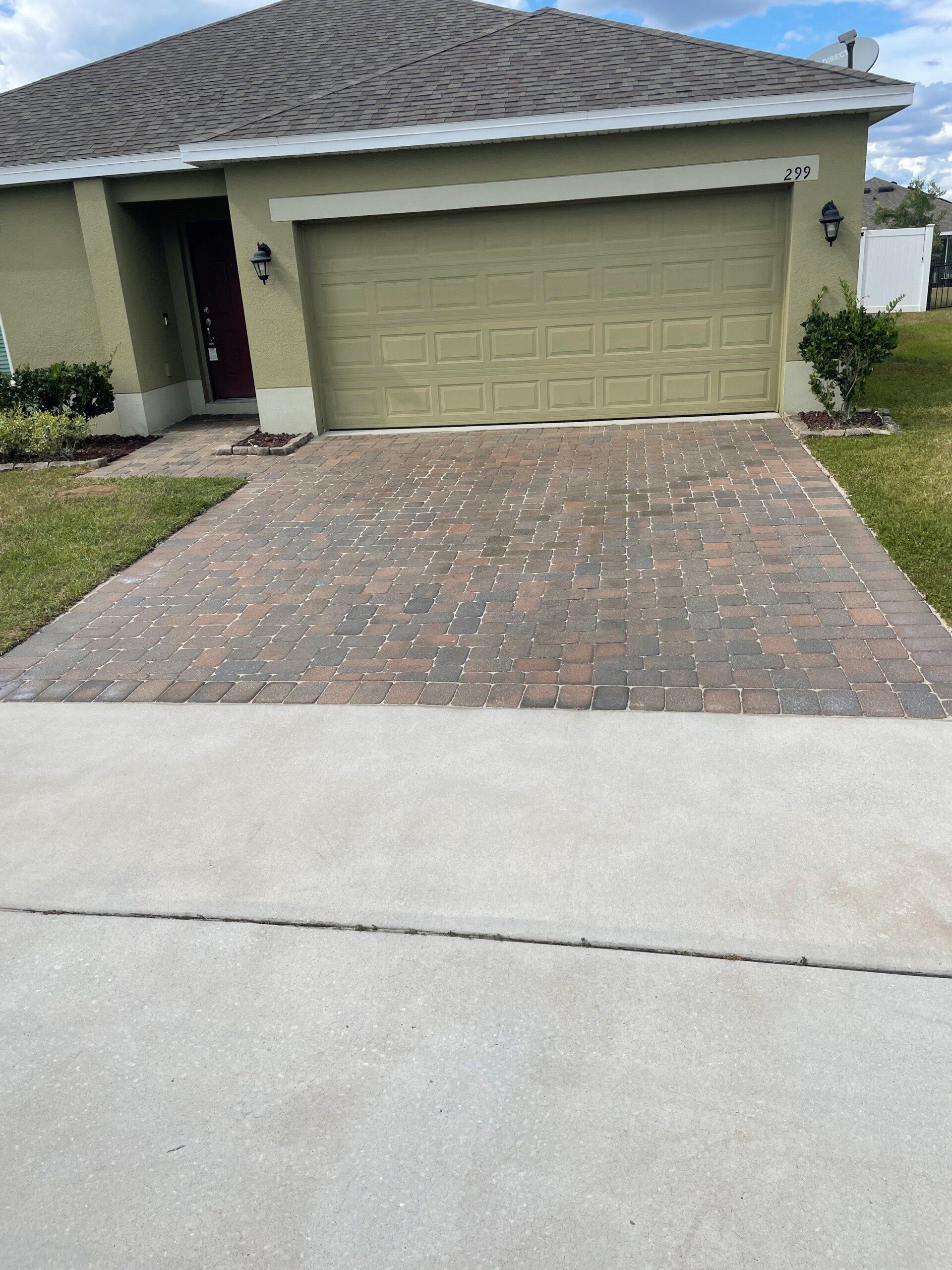 A suburban house exterior with a paved driveway leading to a closed garage, surrounded by a lawn.