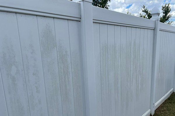 A section of white vinyl fencing with visible streaks and discoloration from dirt or weathering.