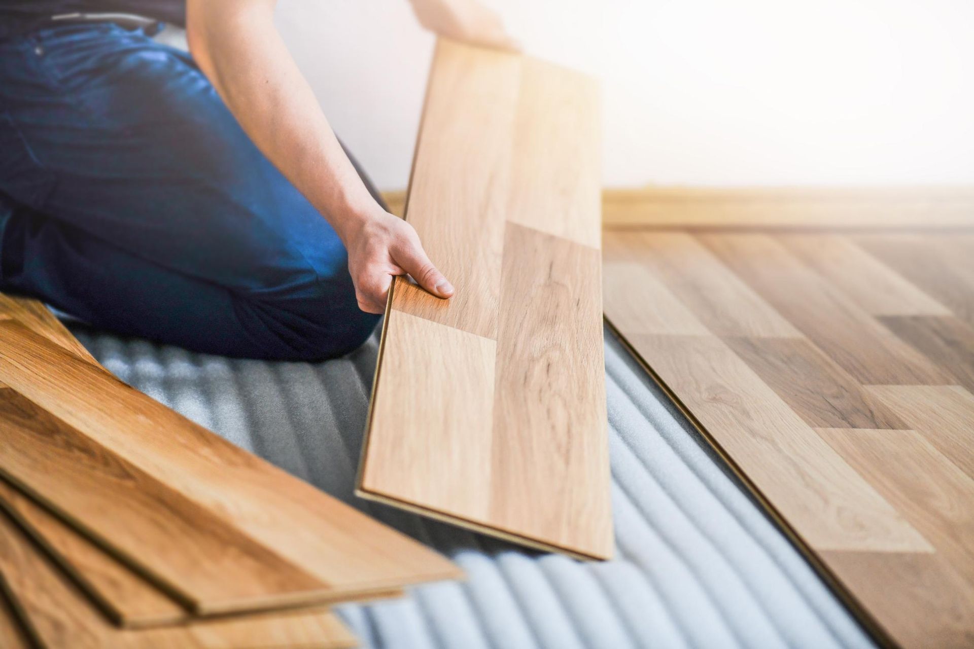 A Person Is Installing A Wooden Floor In A Room — B2B Flooring Solutions In Taree, NSW