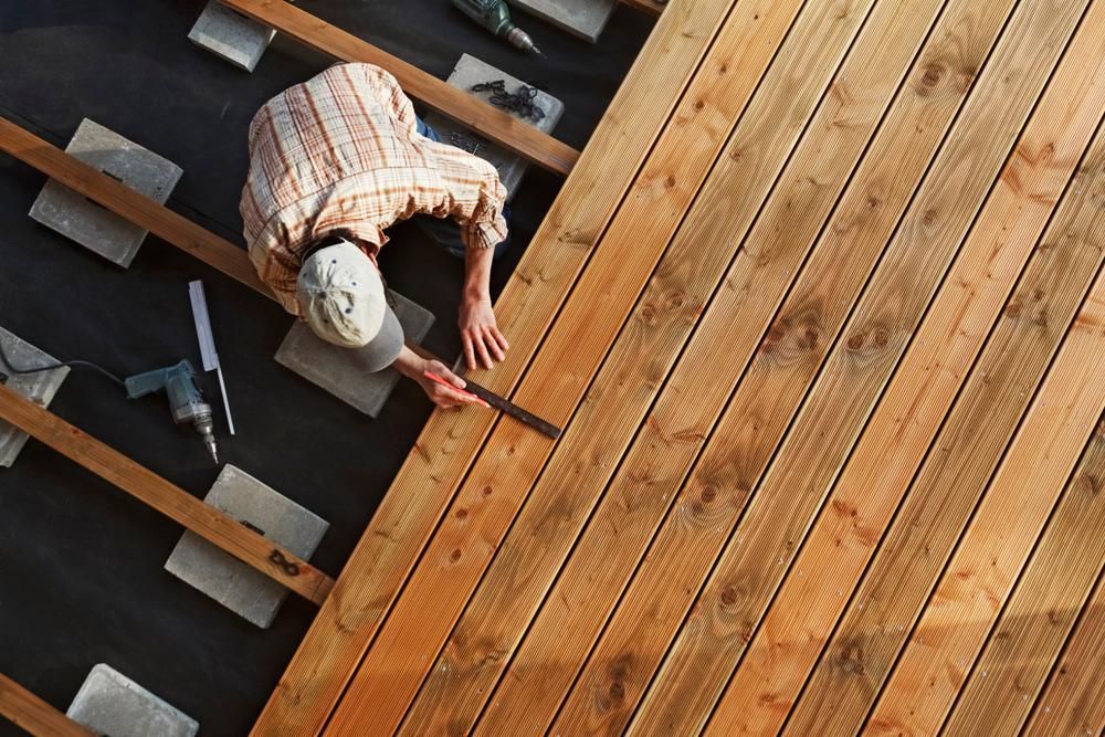 A Man Is Measuring A Piece Of Wood With A Tape Measure — B2B Flooring Solutions In Clarence Valley, NSW