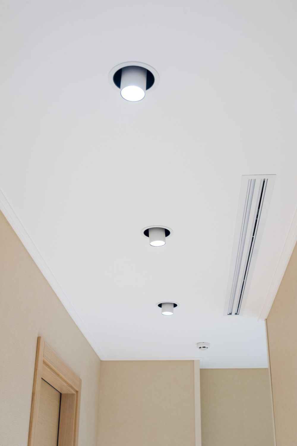 Due persone su una piattaforma elevatrice accanto a un edificio, lavorano sul balcone più alto sotto un cielo azzurro e nuvoloso.