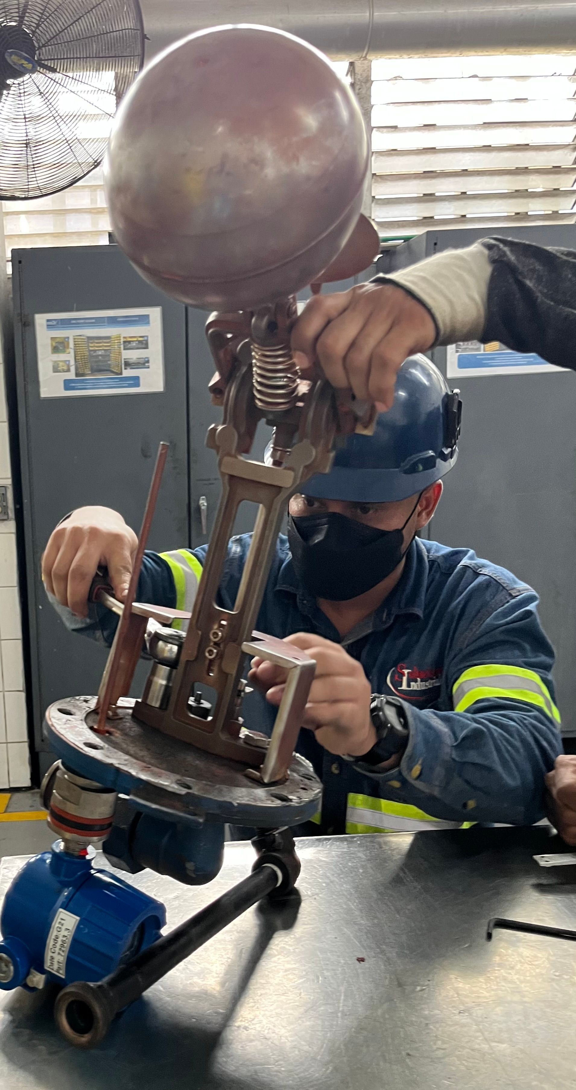 Un hombre que lleva una máscara y un casco está trabajando en una máquina.