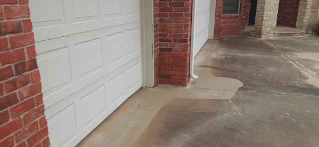 Garage door with water stain on driveway, brick accents.