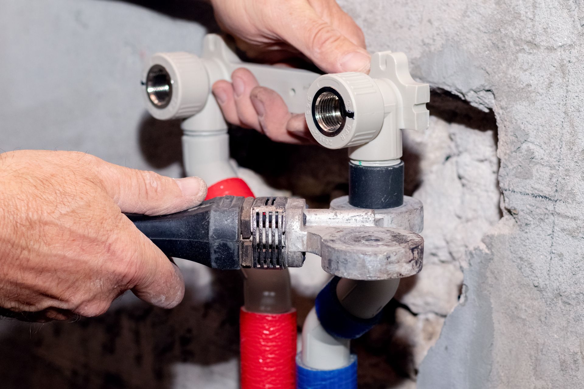 A person is fixing a pipe with a wrench.
