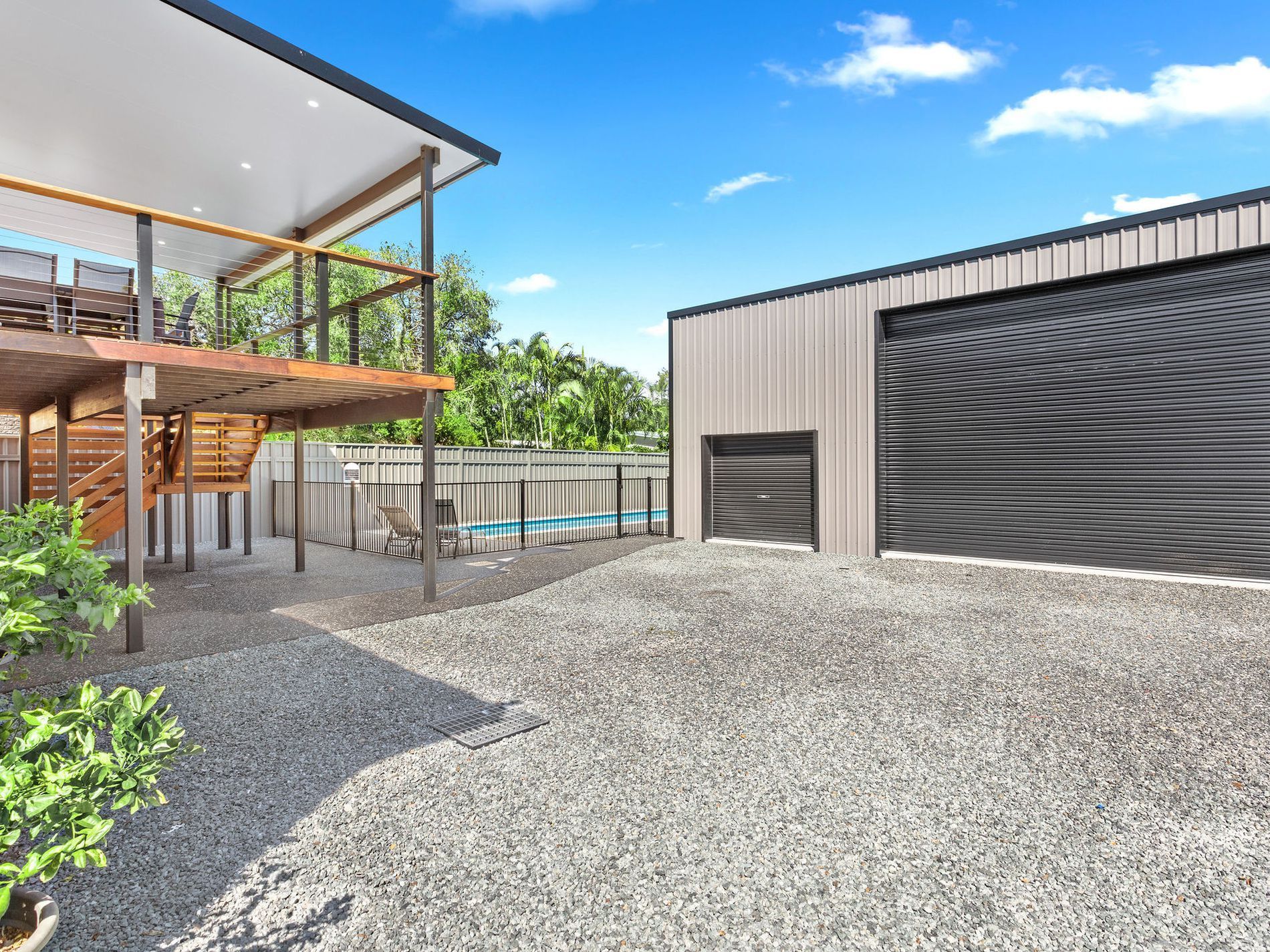 Modern house exterior with gravel driveway, covered patio, and large garage doors — Wade Adams Constructions in Forster, NSW