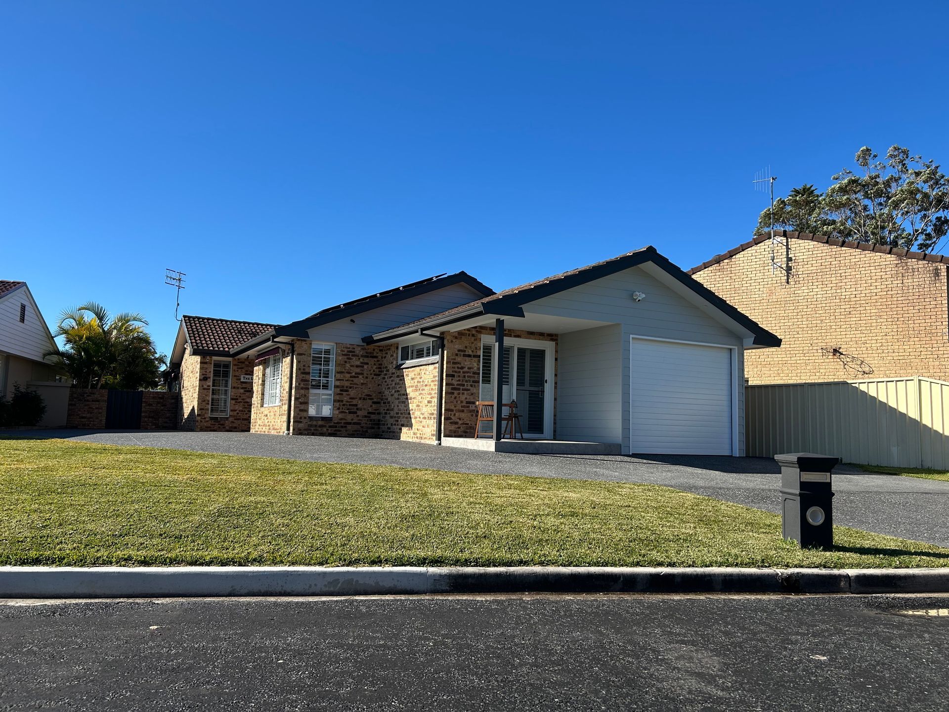Single-story suburban house with stone accents, white garage, and a front lawn — Wade Adams Constructions in Forster, NSW
