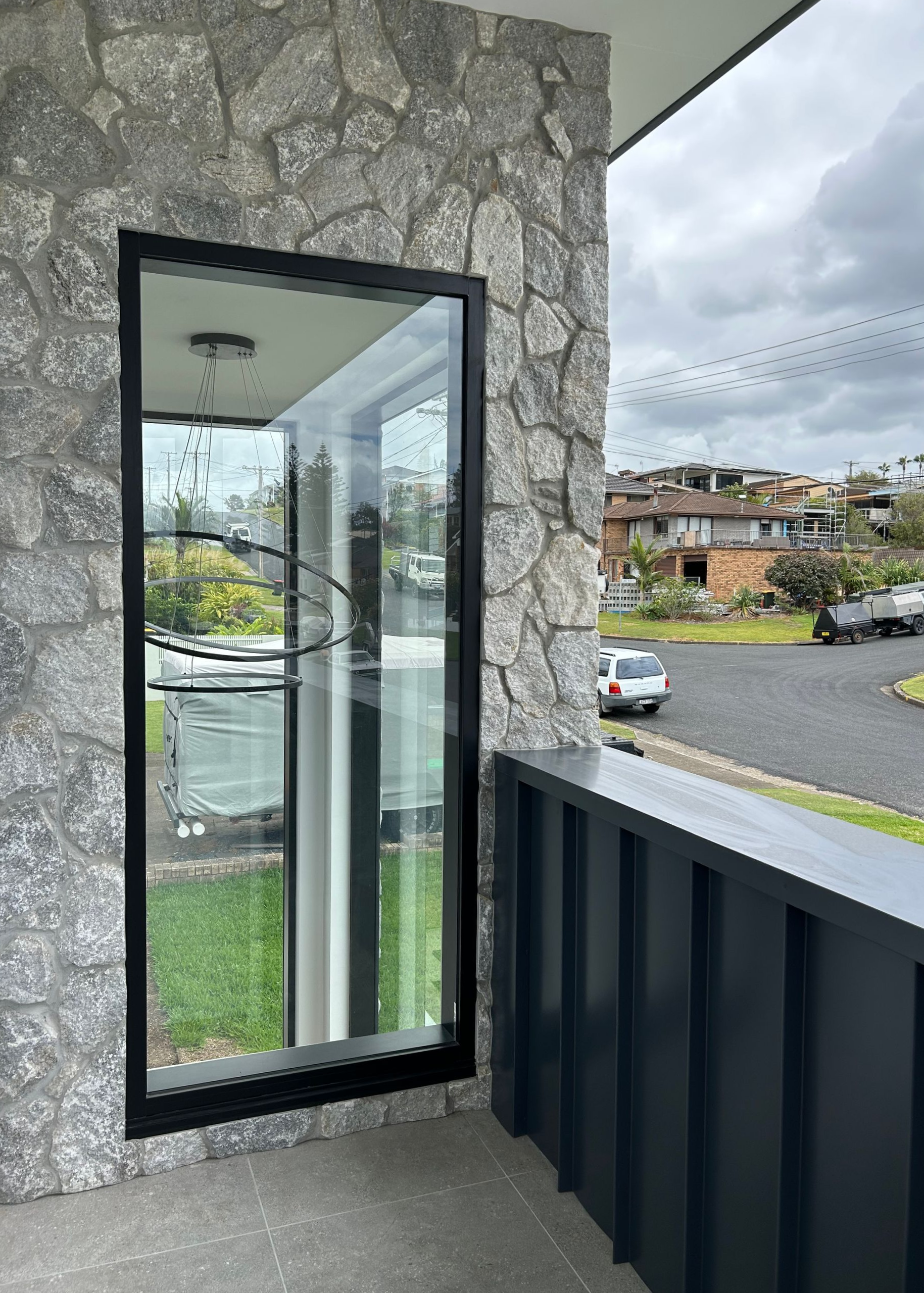 Stone balcony beside an open glass door, overlooking a street and apartment buildings — Wade Adams Constructions in Gloucester, NSW