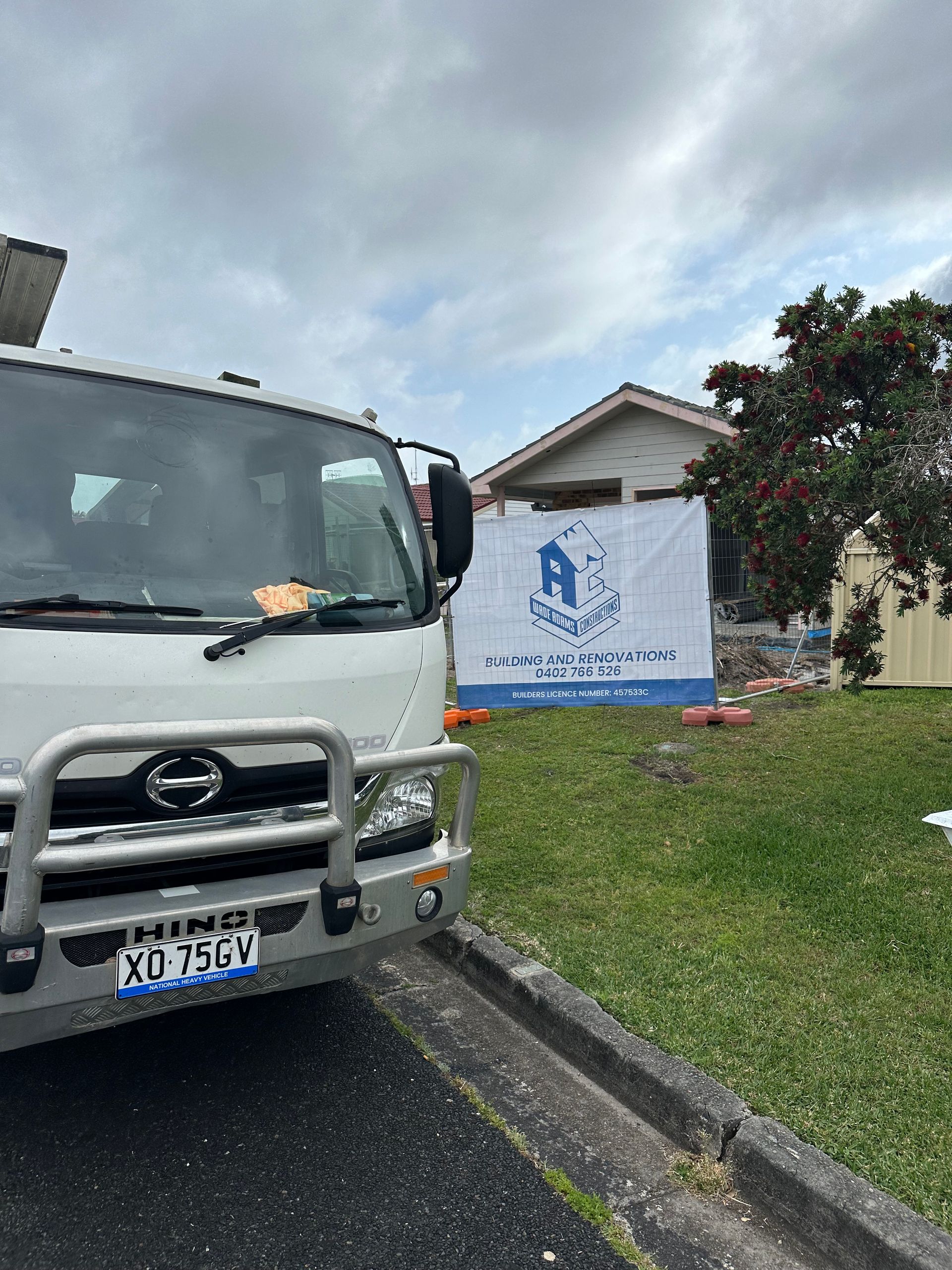 House under renovation with exposed framing, blue tarp roof, and construction tools in the yard — Wade Adams Constructions in Forster, NSW