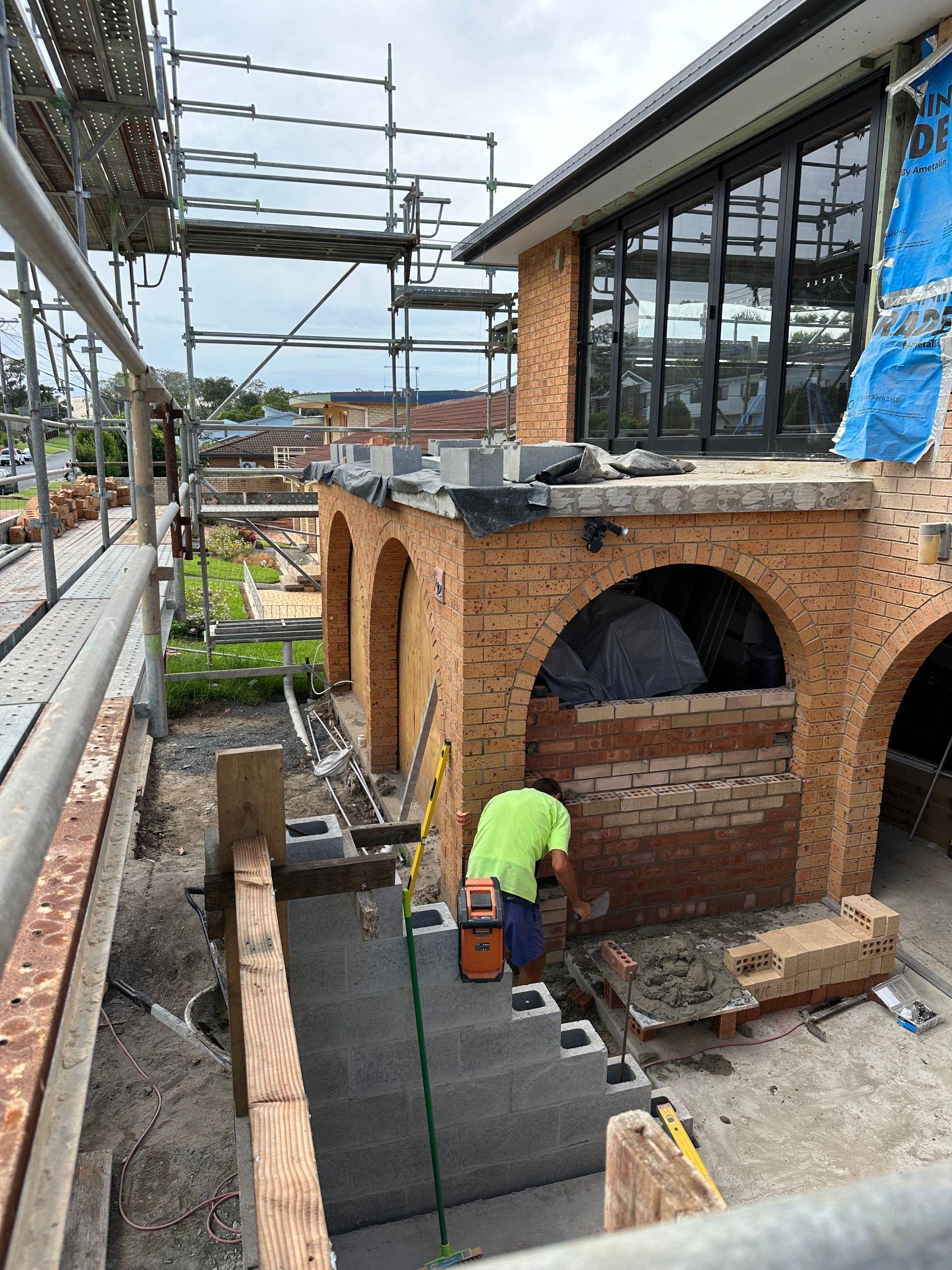 Single-story house exterior under construction with gravel driveway and cloudy sky — Wade Adams Constructions in Forster, NSW