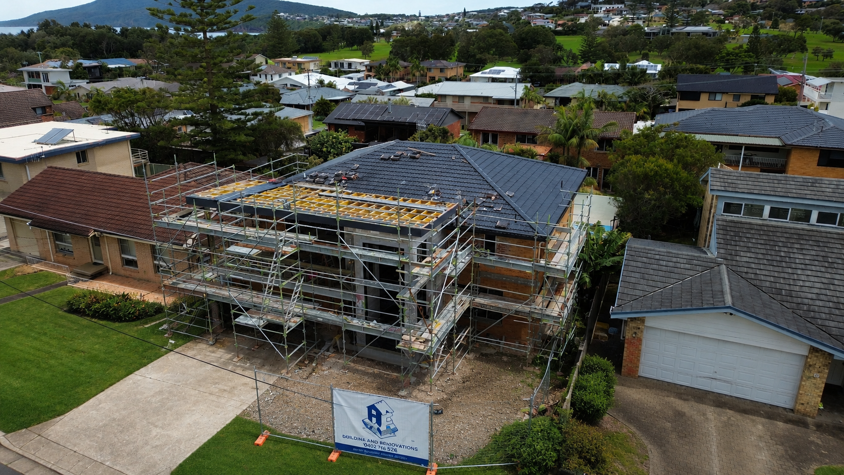 House under construction with scaffolding and a solar-panelled roof in a suburban neighborhood — Wade Adams Constructions in Gloucester, NSW