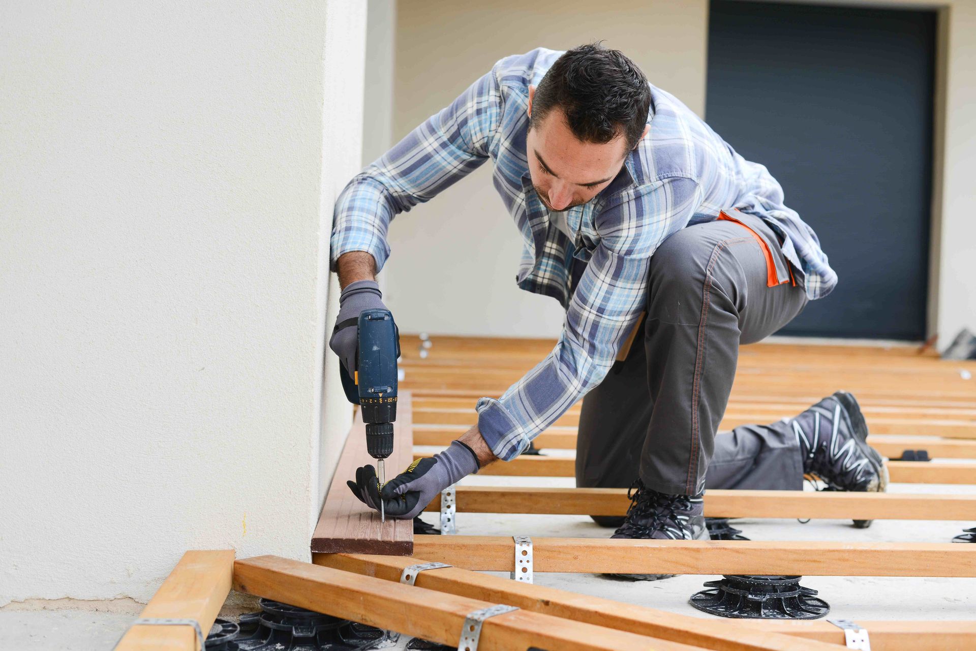 a man is working on a wooden deck with a drill