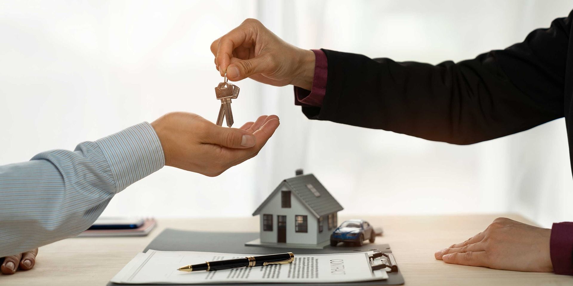 a man is giving a key to another man in front of a model house