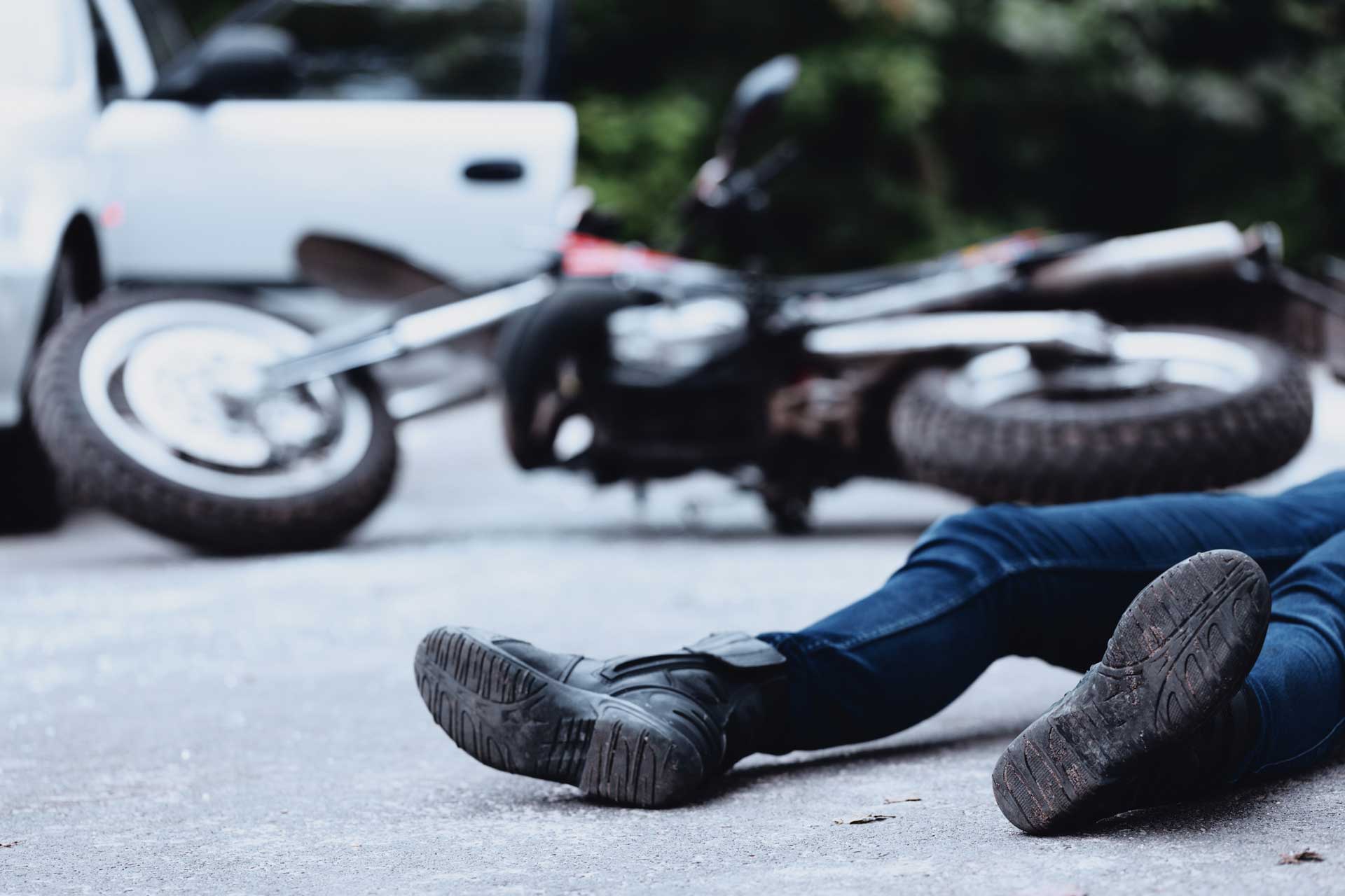 Motorcycle accident scene with a fallen bike and person lying on the road
