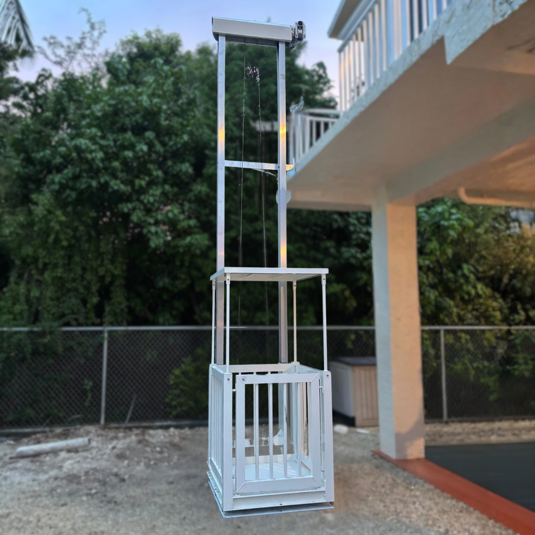 Aerial view of a white residential platform lift next to a house, on a grassy lawn.