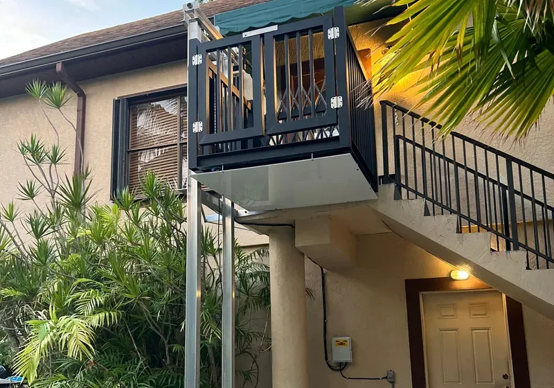 Exterior platform lift attached to a house for wheelchair access to a second-story entrance.