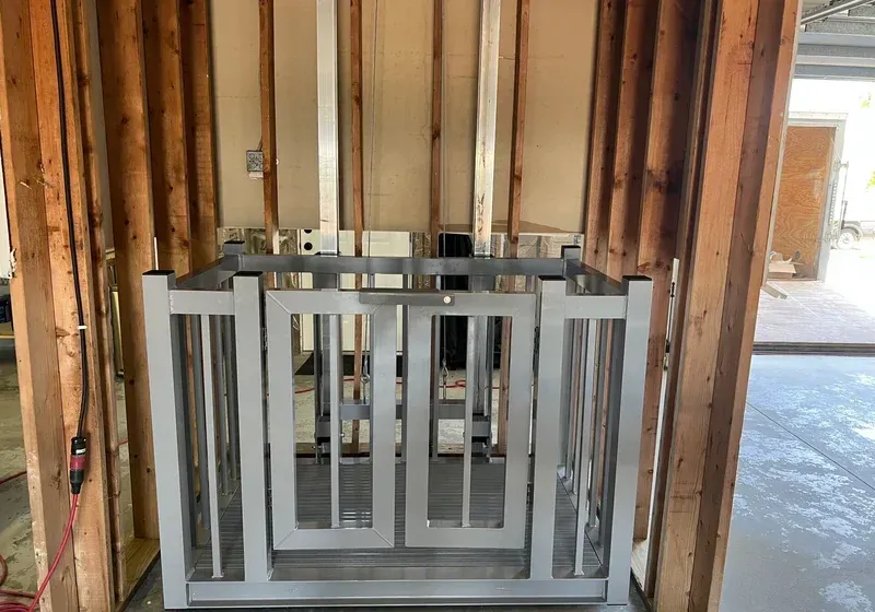 A metal wheelchair lift installed in a partially framed wall.