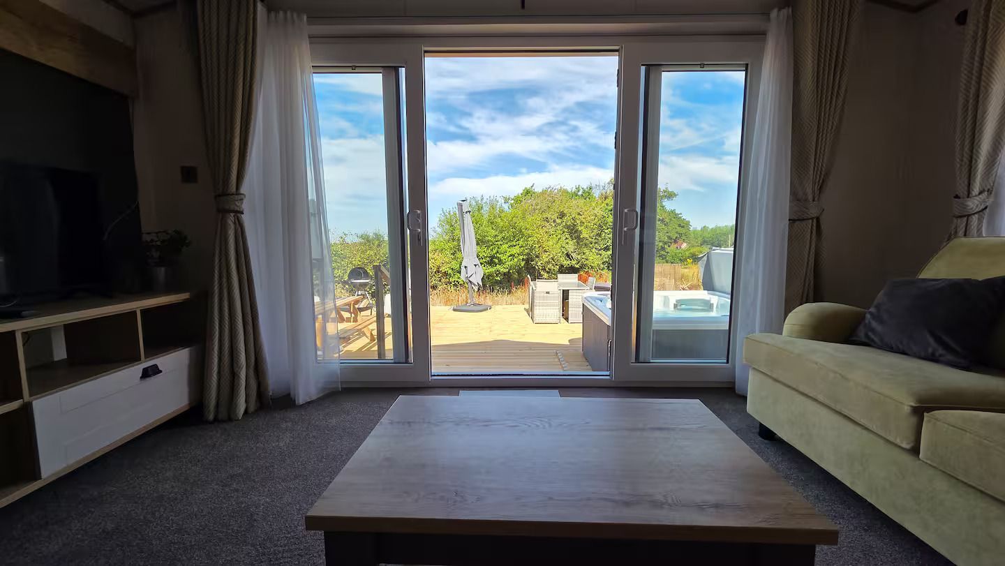 Living room with sofa and coffee table, opening to a bright patio through sliding glass doors
