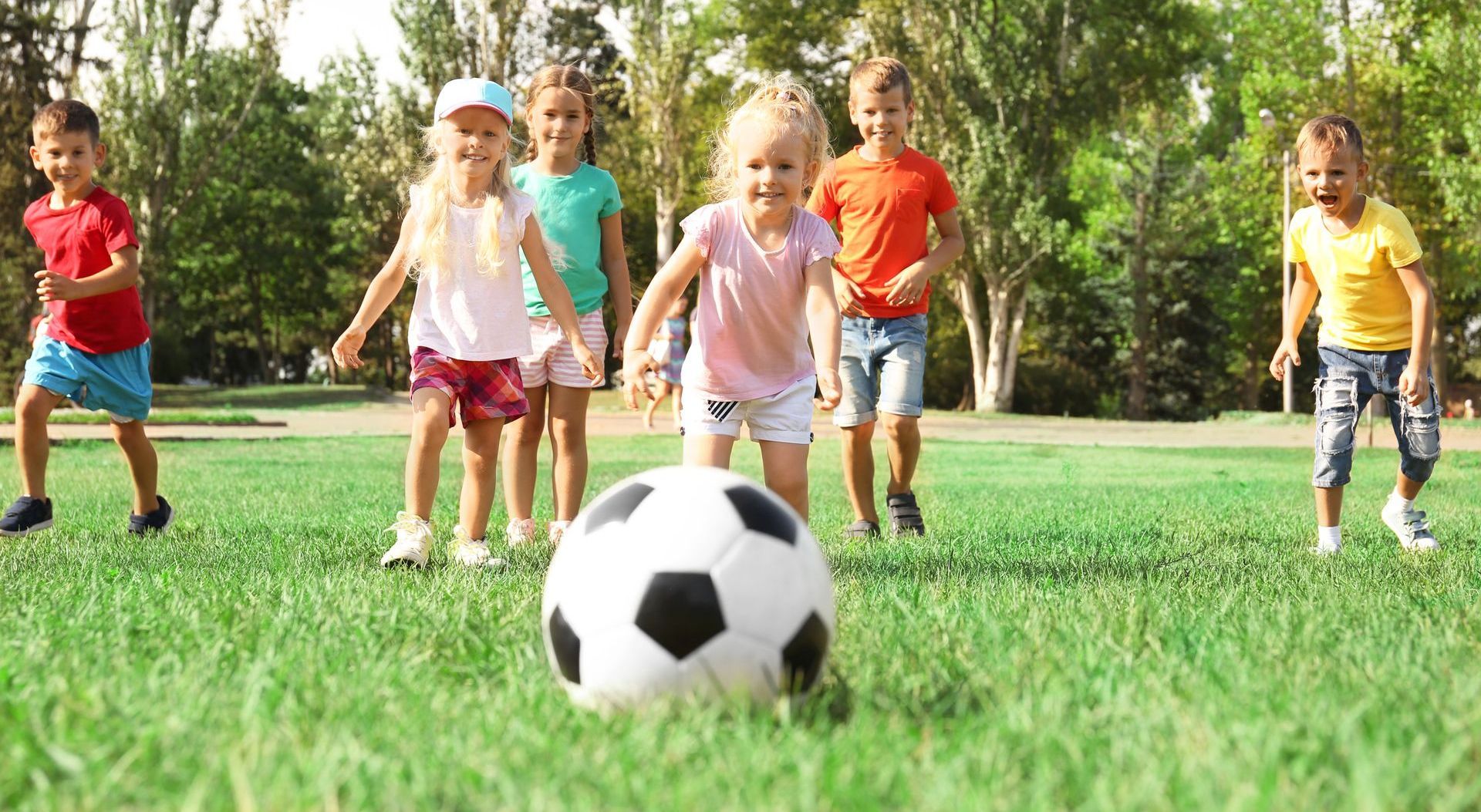 little mixed gender children chasing a soccer ball on a summer day