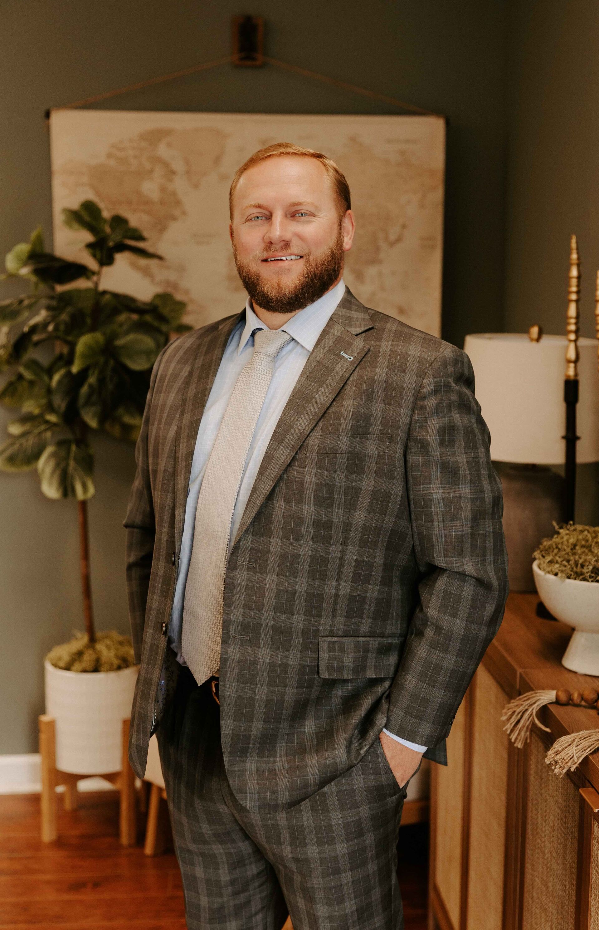 A criminal defense attorney in a suit and tie is standing in a living room with his hands in his pockets.