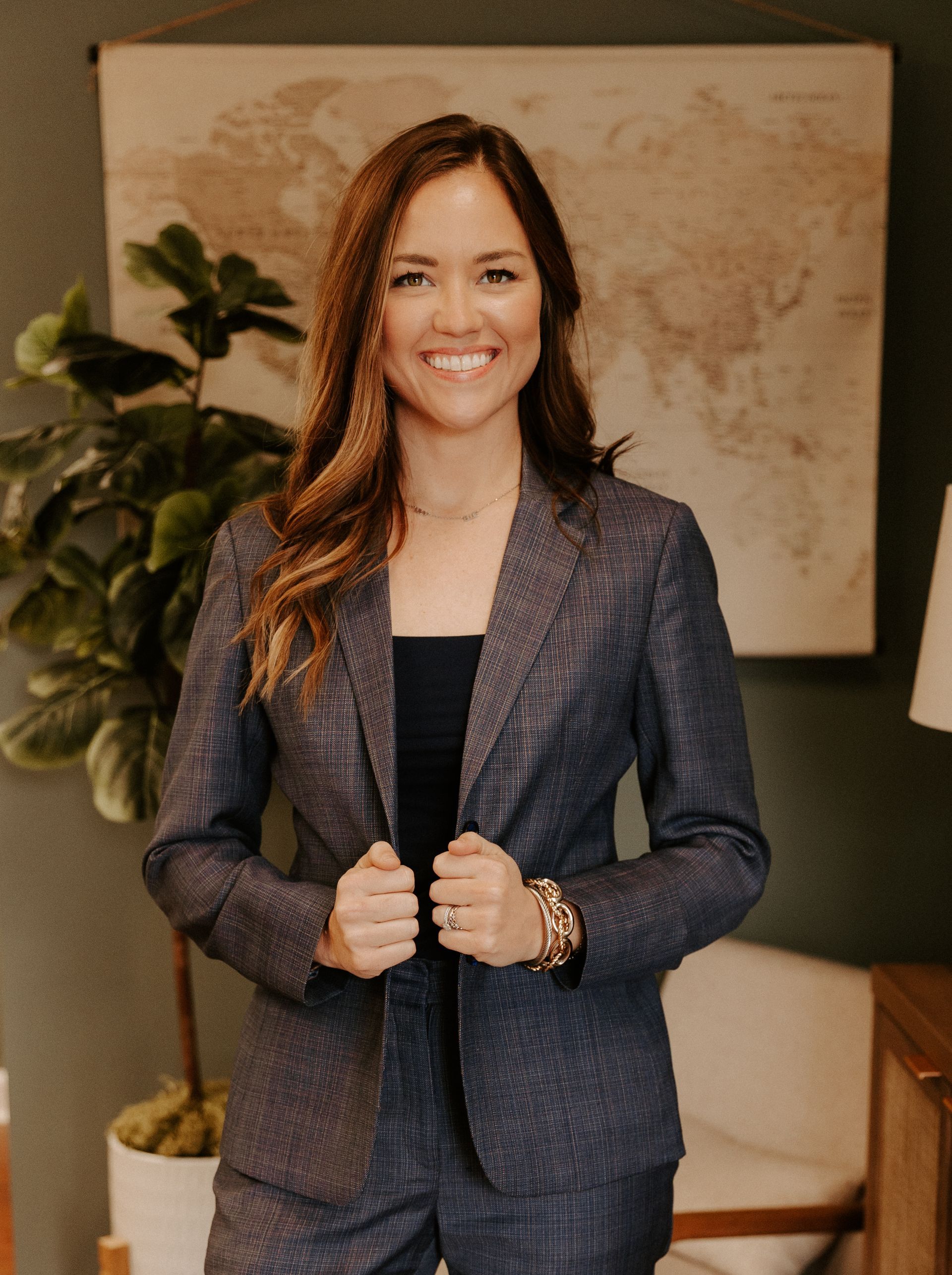 A criminal defense attorney in a suit is standing in front of a map of the world.