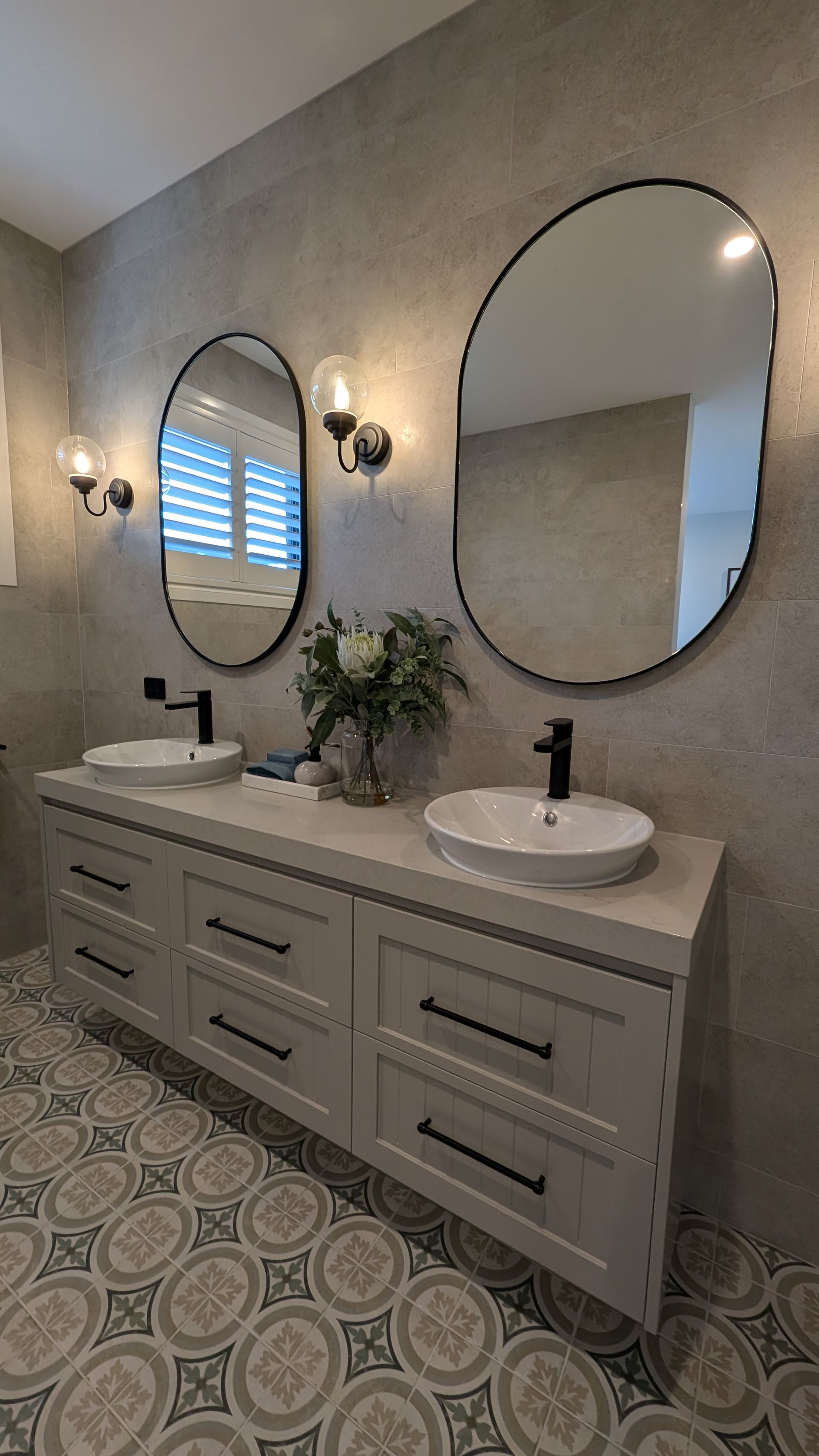 A bathroom with two sinks and two round mirrors.