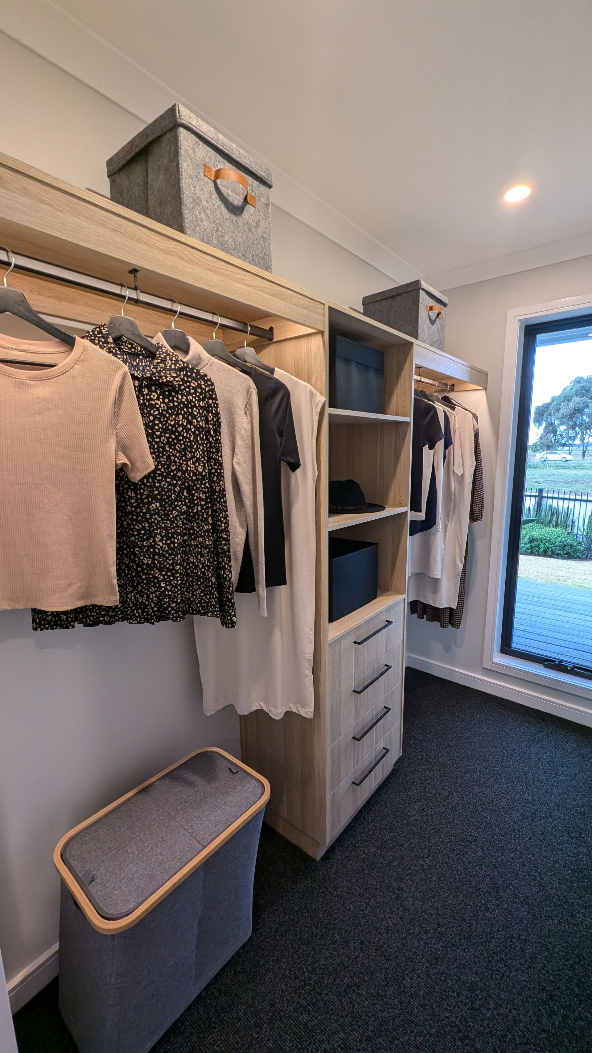 A walk in closet filled with clothes and a laundry basket.