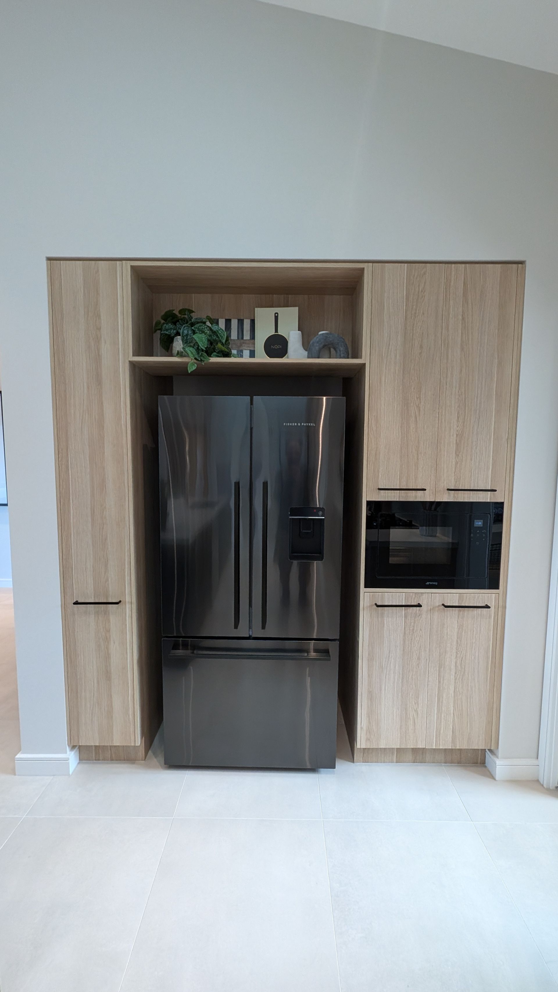 A stainless steel refrigerator is built into a wall in a kitchen.